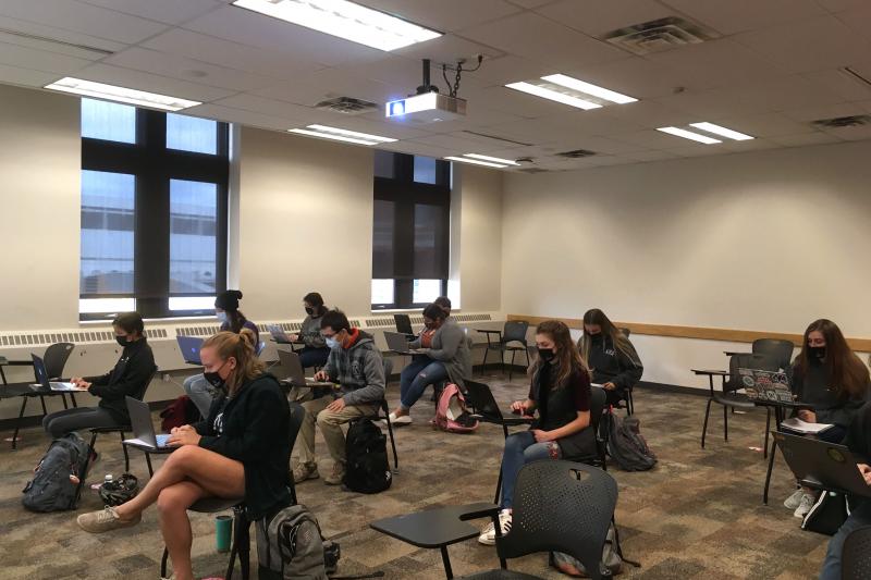 A classroom with students masked and seated at a distance from one another.