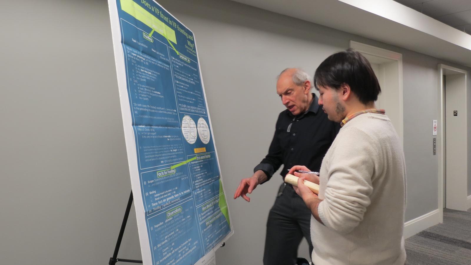 Faculty member Bob Levine talks to a student about a poster